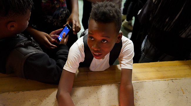 African American boy asking a question on a stage.